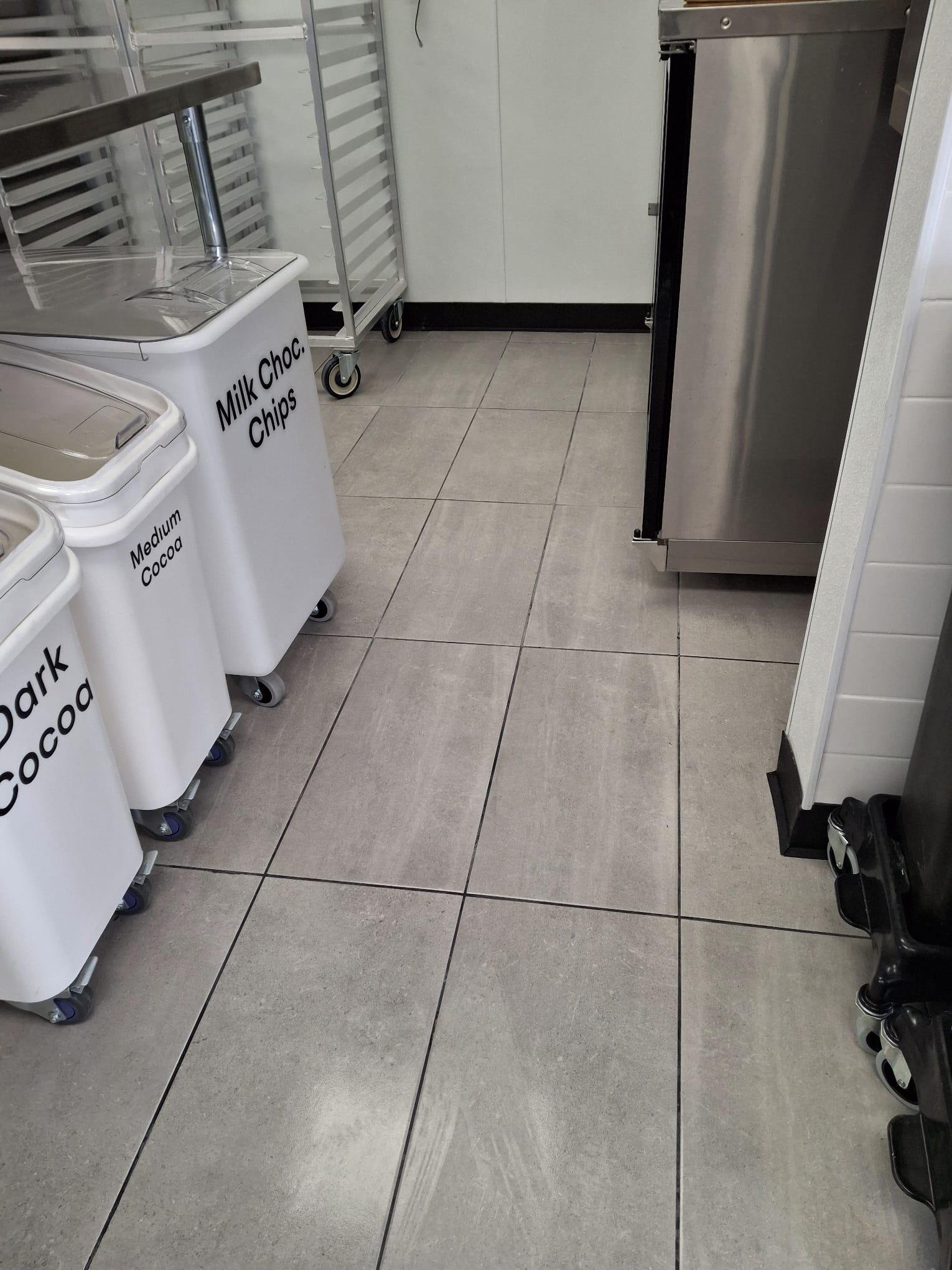 Clean tile floor in a commercial kitchen with ingredient bins and stainless steel equipment