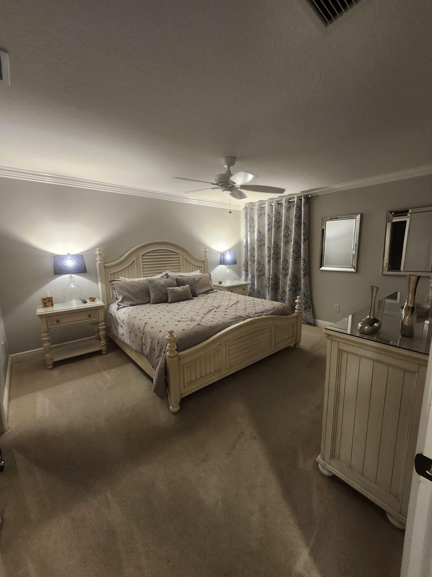 Clean, softly lit bedroom with a made bed and ceiling fan